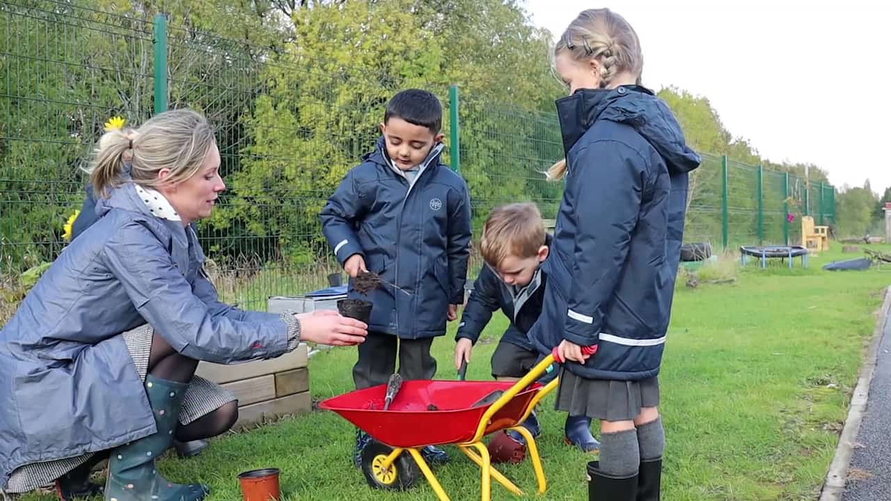 Pupils planting flowers in forest school. 