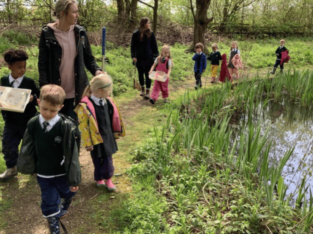 Woodford Primary School pupils from Reception explore next to a pond in Lower Moss Wood
